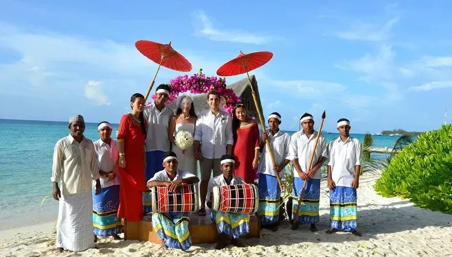 Couple celebrating on a Zanzibar beach with local musicians and red parasols